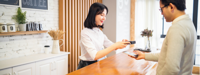 Un cajero de una tienda escanea la billetera digital del teléfono de un cliente que realiza una compra