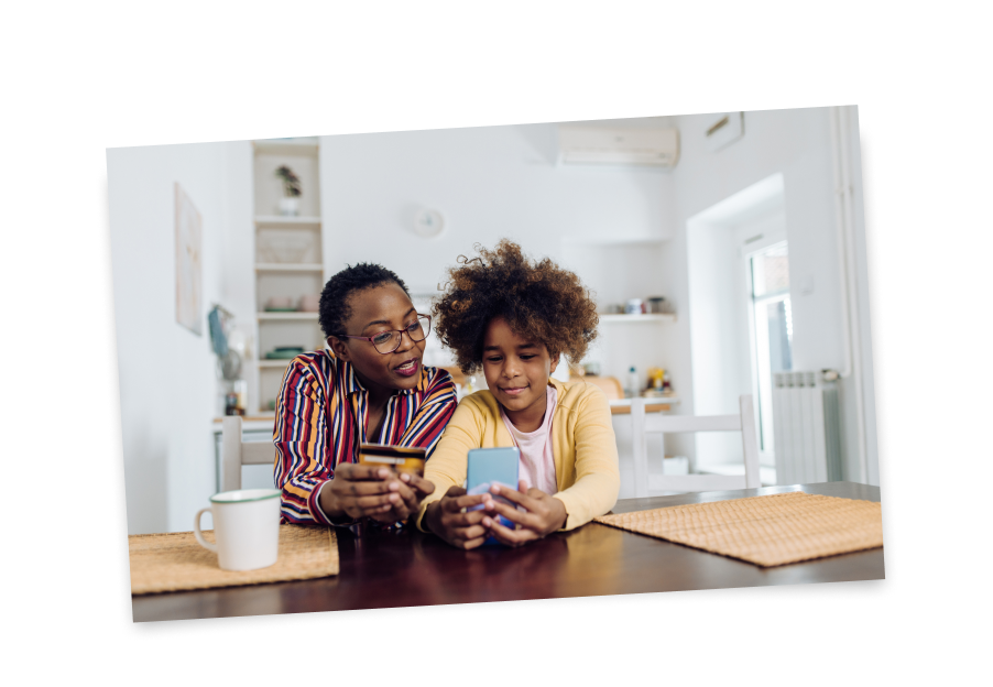 Parent and child look at smart phone with debit card in hand