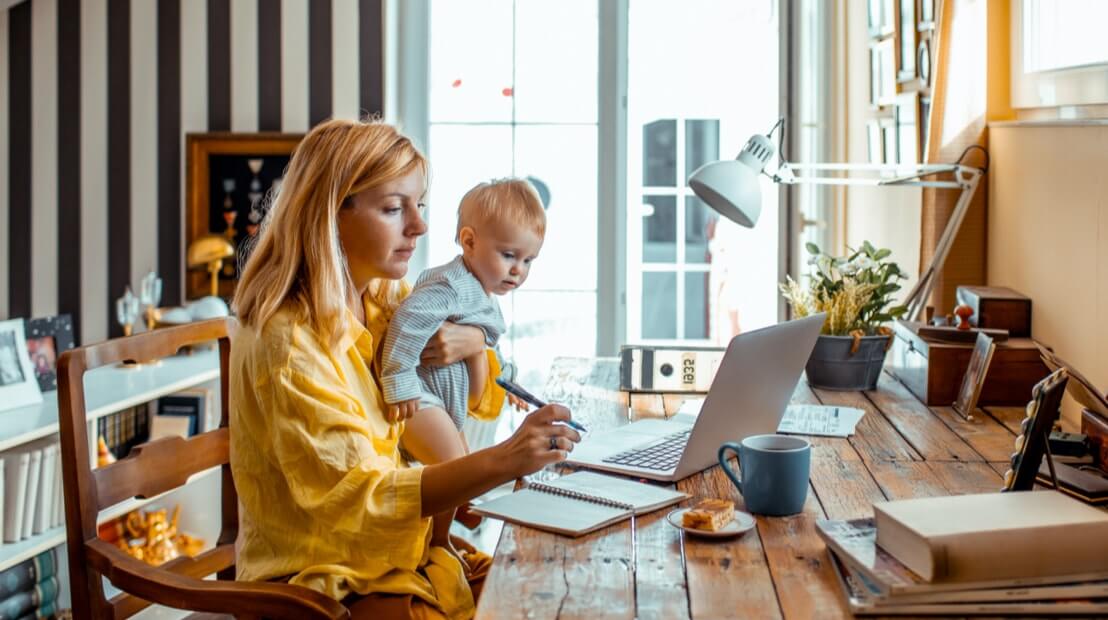 Woman with baby in her lap, working in home office